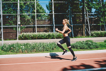 Obraz premium Strong young woman running on track in street