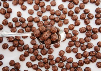 chocolate balls and a spoon with balls. dry breakfast on a white background. View from above.