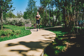 Energetic woman running on alley in park in bright day