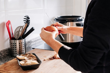 A woman's hands peeling an onion in a kitchen.