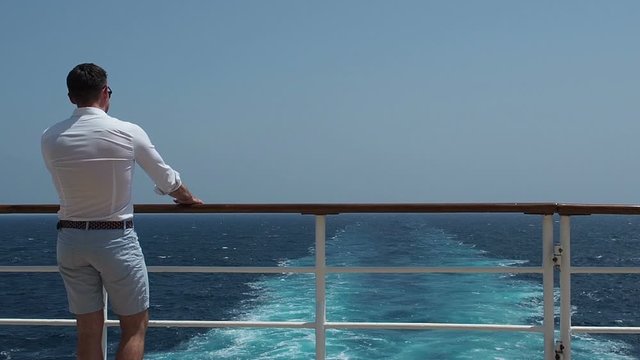 Fashionable man on the empty deck of a cruise liner against the backdrop of the sea waves. Side view, close-up. Concept of style, recreation and travel