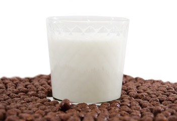 glass of milk and chocolate balls on white. Cereal.