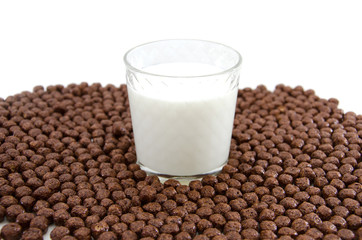 glass of milk and chocolate balls on white. Cereal.