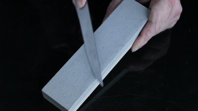 knife sharpening Whetstone on background of black boards.