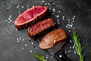 Three  pieces of meat grilled over a meat knife Three types of frying meat, rare, medium, well done. on stone background with copy space for your text