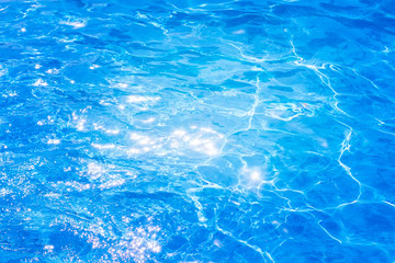 Blue ripped water in swimming pool. background the surface of the water. texture, blue water, bright rays of the sun