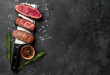 Three  pieces of meat grilled over a meat knife Three types of frying meat, rare, medium, well done. on stone background with copy space for your text