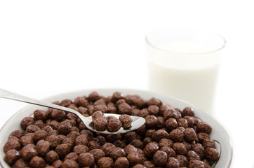 chocolate corn balls in plate and glass of milk on white background.