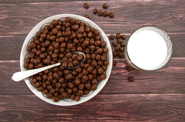 chocolate balls in a plate and a glass of milk. dry breakfast on a wooden background. .