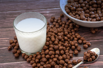 chocolate balls in a plate and a glass of milk. dry breakfast on a wooden background. .