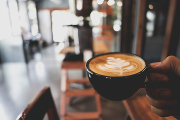 Hand holding Latte cup on blur coffee shop background