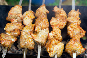 pieces of meat are friend on fire on skewers on grill. close up