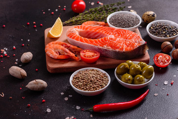 Raw trout red fish steak served with herbs and lemon and olive oil on a dark background