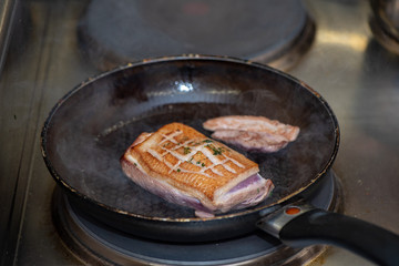 Chef fries duck breast on pan in restaurant kitchen
