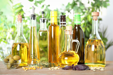 Different sorts of cooking oil in bottles on wooden table