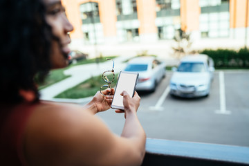 Fototapeta premium African American woman standing on balcony and using cellphone