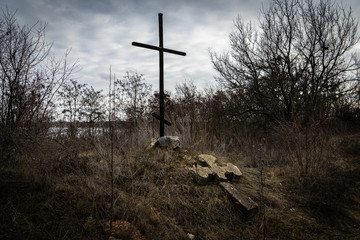 Old stone church cross near an abandoned ruined church