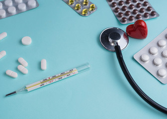 medical pills, capsules, stethoscope and thermometer on a blue background. Medicine concept. Copy space