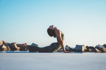 Pretty woman practicing yoga in cobra position in front of sea