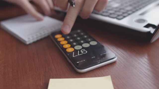 Hands bloggers calculate earnings from the video blog. Close-up of a smartphone calculator, Notepad, and a hand with a pen. An office worker calculates the company's revenue