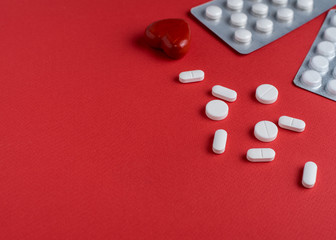 Medicine pills, capsules and stethoscope on a red background. Medicine concept. Copy space