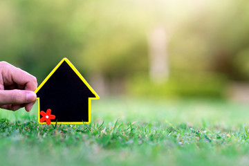 Hand and Mini house on the grass nature background