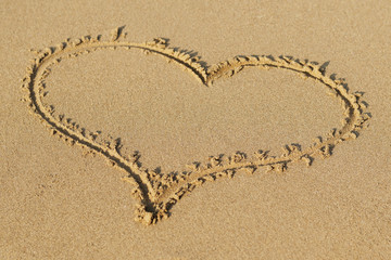 Heart drawn in the sand. Beach background. Top view.