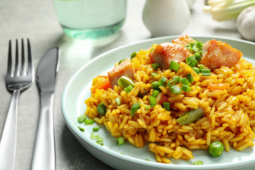 Delicious rice pilaf with vegetables and chicken on light grey table, closeup