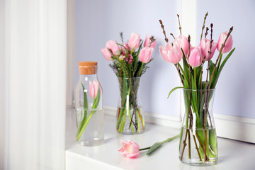 Beautiful bouquet with spring pink tulips on white window sill indoors