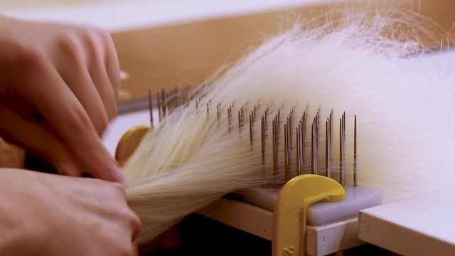 Wig production, female hands close-up. Wig Hair Combing