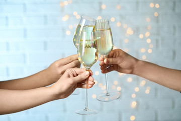 People clinking glasses of champagne against blurred lights, closeup