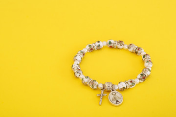 Ornate Rosary bracelet on yellow with copy space