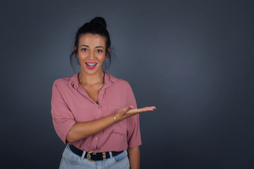 Positive glad female says: wow how exciting it is, has amazed expression, shows something on blank space with open hand over isolated gray background. Advertisement concept.