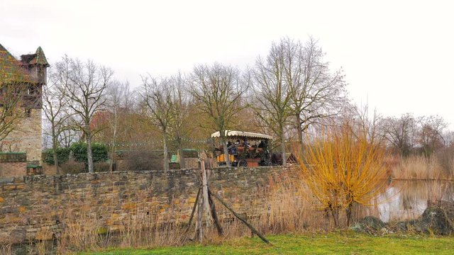 Carruaje lleno de gente y decorado tirado por dos caballos percherones y paseando por aldea medieval