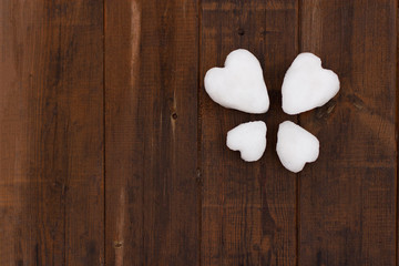 four-leaf symbol of white hearts made of snow on wooden brown boards, place for the inscription