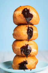 Doughnuts stack on a blue plate. Chocolate Berliner donuts tower
