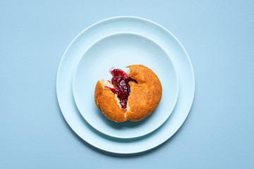 One jelly donut on a plate. German doughnut with raspberry jam