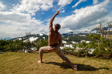 Anonymous man doing yoga in mountains