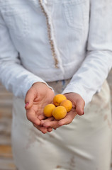 girl in bright clothes holds apricots in her hands