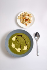 Broccoli puree soup with cream and balsamic sauce and a plate with breadcrumbs