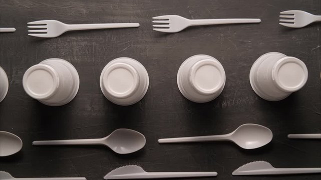 plastic problem concept, stop motion animation, place for text, white plastic dishes move on black background 4k