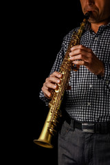 Naklejka premium soprano saxophone in hands on a black background