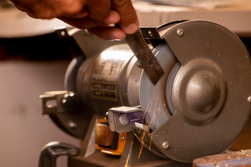 luthier using grinder to prepare metal part