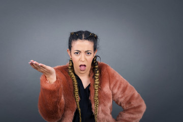 What the hell are you talking about, nonsense. Studio shot of frustrated female with blonde hair gesturing with raised palm, frowning, being displeased and confused with dumb question over gray wall.