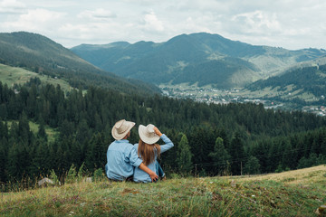 Fototapeta na wymiar Loving couple sitting on mountain meadow and enjoying view of nature