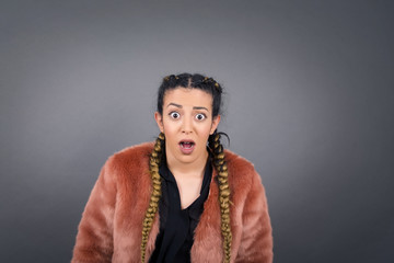Emotional attractive female with opened mouth expresses great surprisment and frighteness, poses against white concrete background, stares at camera. Unexpected shocking news and human reaction.