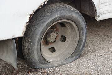 Fototapeta na wymiar one black flat tire on a white car on gray asphalt in the street