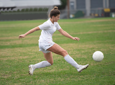 Young girl playing in a soccer game and kicking the ball