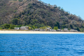 Fototapeta premium A distant view on a fishing cottage, located on a seashore of a small island next Flores, Indonesia. Clear, turquoise coloured water displaying coral reef. Solitude and calmness. Simple construction