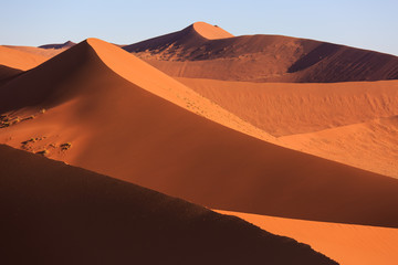 Naklejka na ściany i meble Beautiful landscape with red huge sand dunes at sunset in desert. Sossusvlei, Namib Naukluft National Park, Namibia. Stunning natural geometry without people